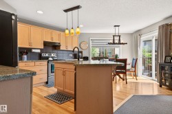 Light wood cabinetry with granite-style countertops and a dark tile backsplash - 