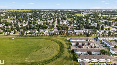 Expansive aerial perspective showcasing a residential area with a mix of single-family homes and multi-family townhomes - 33 Brookside Avenue, Spruce Grove, AB 