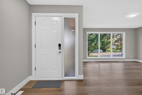Entryway with a white paneled door featuring a digital lock, frosted sidelight, and wood-finish flooring - 33 Brookside Avenue, Spruce Grove, AB 
