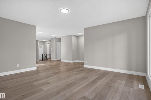 Spacious room featuring wood-finish flooring, light grey painted walls, white baseboards, and recessed lighting - 33 Brookside Avenue, Spruce Grove, AB 