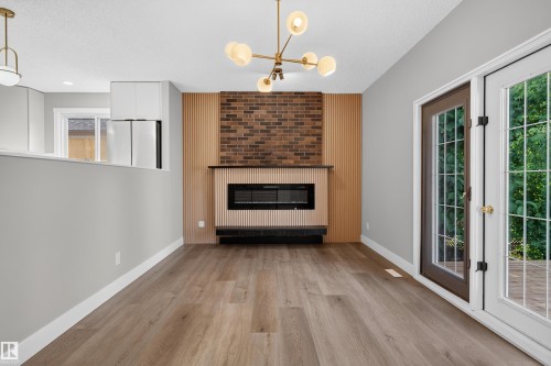 Modern fireplace with brick surround and vertical wood paneling - 33 Brookside Avenue, Spruce Grove, AB 