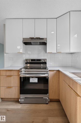 Kitchen featuring a stainless steel range, white subway tile backsplash, and light wood-finish lower cabinetry - 33 Brookside Avenue, Spruce Grove, AB 
