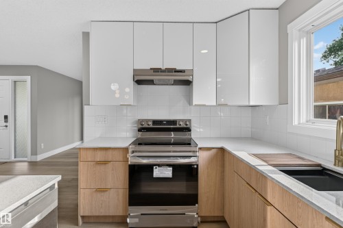 Modern kitchen featuring white upper cabinetry, wood-finish lower cabinetry, white subway tile backsplash, and light-toned countertops - 33 Brookside Avenue, Spruce Grove, AB 
