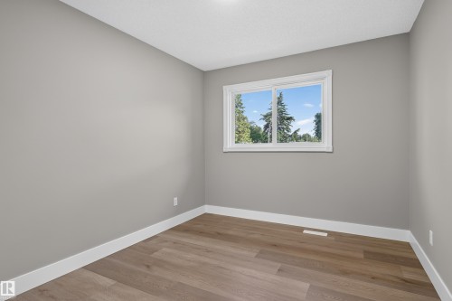 Room featuring a window with white trim, wood-finish flooring, light gray wall paint, and white baseboards - 33 Brookside Avenue, Spruce Grove, AB 