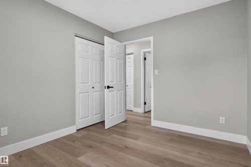 Spacious room featuring light wood-finish flooring, neutral wall tones, white trim, and a paneled bifold closet door - 33 Brookside Avenue, Spruce Grove, AB 
