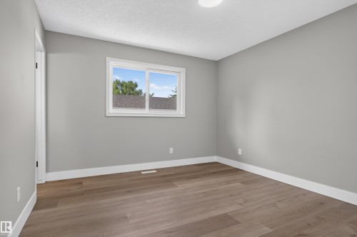 Room featuring wood-finish flooring, light grey painted walls, white baseboards, and a white window frame - 33 Brookside Avenue, Spruce Grove, AB 