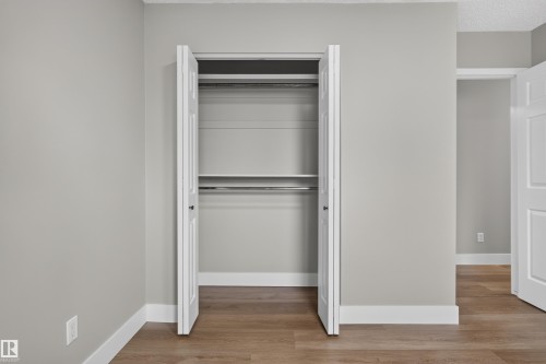 Double-door closet featuring a built-in shelf and two hanging rods - 33 Brookside Avenue, Spruce Grove, AB 