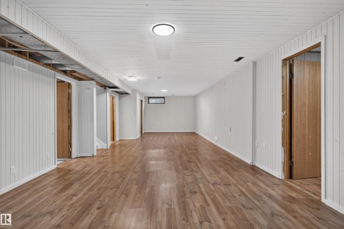 Spacious room featuring wood-finish flooring and white vertical paneling - 33 Brookside Avenue, Spruce Grove, AB 