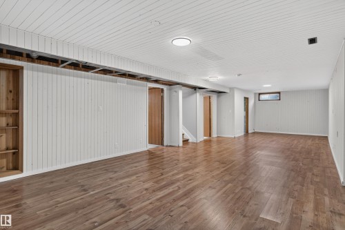 Expansive open-concept room featuring wood-finish flooring, white paneled walls, and a white paneled ceiling - 33 Brookside Avenue, Spruce Grove, AB 