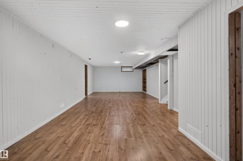Spacious lower-level room featuring wood-finish flooring, white vertical plank walls, and recessed ceiling lighting - 33 Brookside Avenue, Spruce Grove, AB 