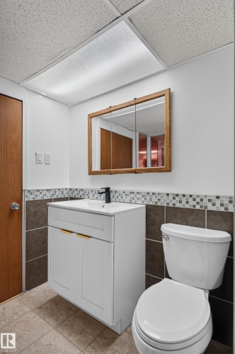 White vanity with gold-tone hardware and integrated sink, complemented by a matte black faucet - 33 Brookside Avenue, Spruce Grove, AB 