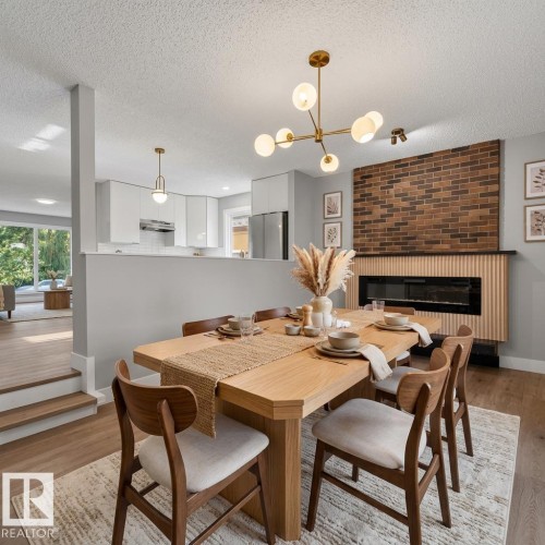 AI Generated -Dining area featuring wood-finish flooring, a contemporary linear chandelier, and a fireplace with a brick surround and wood slat details - 33 Brookside Avenue, Spruce Grove, AB 