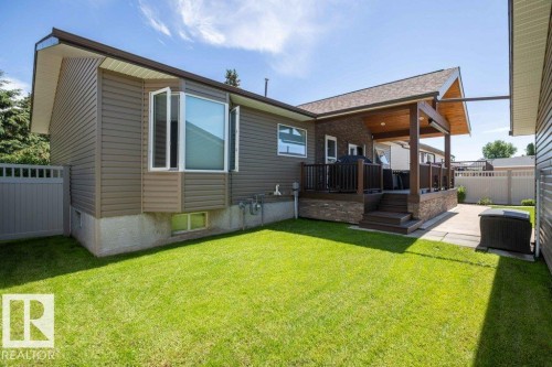 Exterior featuring horizontal siding, a covered deck with wood posts and railings, and a manicured lawn - 10420 111 Avenue, Westlock, AB 