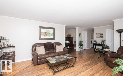Spacious interior featuring wood-finish flooring, light-toned walls with white trim, and white crown molding - 10420 111 Avenue, Westlock, AB 