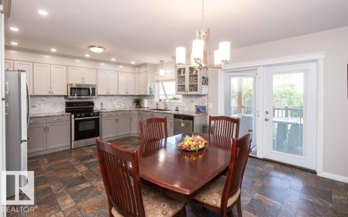 Kitchen featuring gray cabinetry, stainless steel appliances, and a mosaic tile backsplash - 10420 111 Avenue, Westlock, AB 