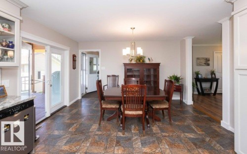 Dining area featuring multi-toned tile flooring, a chandelier, and double patio doors opening onto an outdoor deck - 10420 111 Avenue, Westlock, AB 