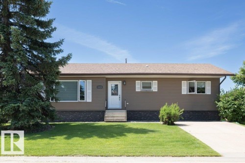 Single-story residence featuring brown horizontal siding and a dark brown shingle roof - 10420 111 Avenue, Westlock, AB 