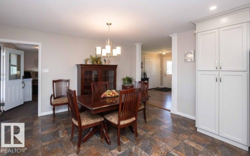 Spacious dining area featuring multi-toned tile flooring, recessed lighting, and a contemporary chandelier - 10420 111 Avenue, Westlock, AB 