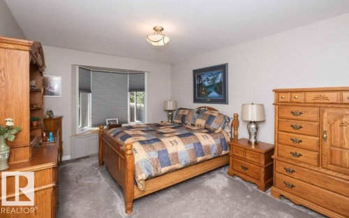 Carpeted bedroom with a bay window featuring cellular shades - 10420 111 Avenue, Westlock, AB 