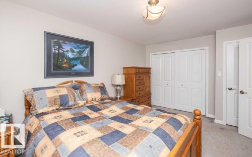 Bedroom featuring neutral wall paint, gray carpeting, a semi-flush ceiling light fixture, and white bi-fold closet doors - 10420 111 Avenue, Westlock, AB 