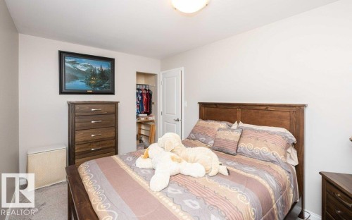 Bedroom featuring light neutral wall paint, gray carpet flooring, a built-in closet with an open doorway, and a flush-mount ceiling light fixture - 10420 111 Avenue, Westlock, AB 