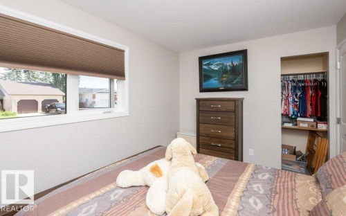 Light-filled room featuring neutral wall paint, wood-finish flooring, a double window with blinds, and an open closet space - 10420 111 Avenue, Westlock, AB 