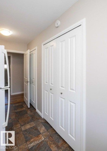 Hallway featuring multi-toned tile flooring, white bi-fold doors, and recessed lighting - 10420 111 Avenue, Westlock, AB 