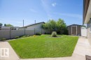 Expansive backyard featuring a lush lawn, mature trees, concrete pathways, a detached storage shed, and durable privacy fencing - 10420 111 Avenue, Westlock, AB 