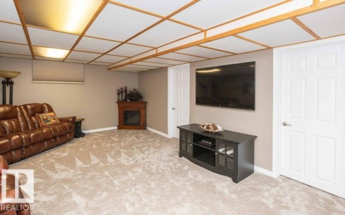 Spacious room featuring neutral carpeting, a drop ceiling with recessed lighting, and light beige walls - 10420 111 Avenue, Westlock, AB 