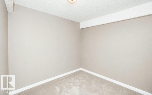 Neutral-toned wall paint with white baseboards and textured carpet flooring - 10420 111 Avenue, Westlock, AB 