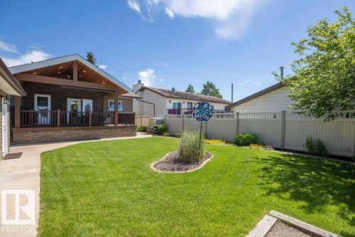 Expansive backyard featuring a manicured lawn, concrete pathway, and mature tree - 10420 111 Avenue, Westlock, AB 