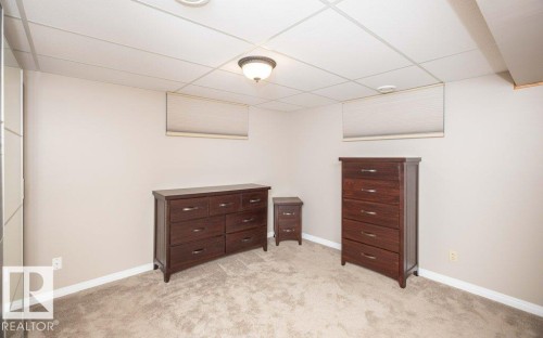 Carpeted room featuring a drop ceiling with recessed lighting and a central light fixture - 10420 111 Avenue, Westlock, AB 