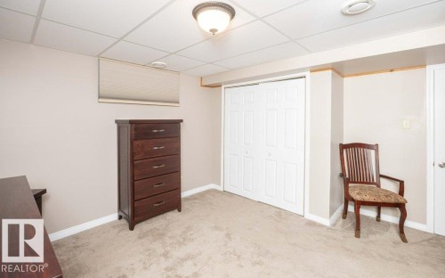 Carpeted room featuring a drop ceiling with recessed lighting and a flush mount light fixture - 10420 111 Avenue, Westlock, AB 