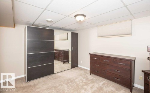 Carpeted room featuring a white acoustic tile ceiling, recessed lighting, and a window with a cellular shade - 10420 111 Avenue, Westlock, AB 
