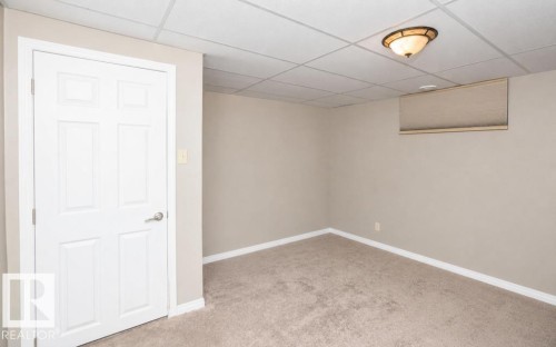 Neutral-toned room featuring a drop ceiling, flush-mount lighting, and carpet flooring - 10420 111 Avenue, Westlock, AB 
