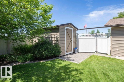 Backyard featuring a functional storage shed with a barn-style door, white vinyl fencing and gates, and a gravel pad - 10420 111 Avenue, Westlock, AB 