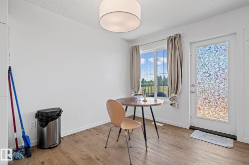 Bright dining area featuring wood-finish flooring, a contemporary drum ceiling light, and a window with outdoor views - 16 19904 31 Avenue, Edmonton, AB 