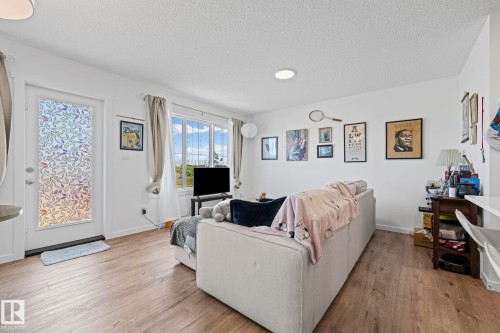 Bright living area featuring wood-finish flooring, white walls, and a white ceiling - 16 19904 31 Avenue, Edmonton, AB 