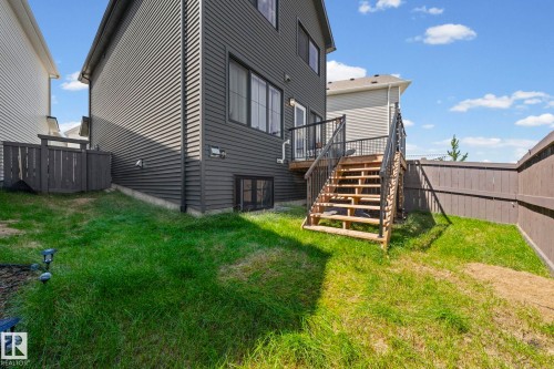 Exterior deck with wooden stairs, black metal railings, and a sliding glass door - 16 19904 31 Avenue, Edmonton, AB 