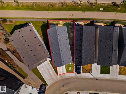 Aerial perspective showcasing a property with a dark shingle roof, a concrete driveway, and a front yard with green grass - 16 19904 31 Avenue, Edmonton, AB 