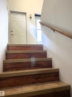 Staircase featuring wood-finish risers, tiled treads, and a natural wood handrail - 