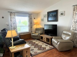 Living space featuring wood-finish flooring, a large window with blinds, and light-toned wall finishes - 