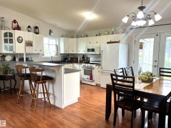 Spacious kitchen featuring wood-finish flooring, white cabinetry, dark countertops, and stainless steel appliances - 