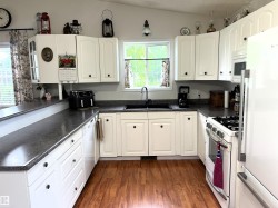 U-shaped kitchen featuring white cabinetry, wood-finish flooring, and dark countertops - 