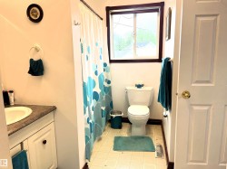 Bathroom featuring a single window, white paneled door, and a white toilet - 