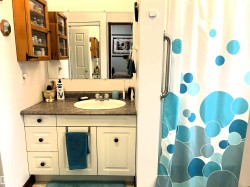 Bathroom featuring a white vanity with a built-in sink, a speckled countertop, and a wall-mounted mirror - 