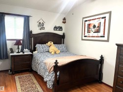 Bedroom featuring wood-finish flooring, a window with horizontal blinds, and a ceiling fan - 