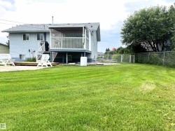 Spacious backyard featuring a manicured lawn, screened-in elevated deck, and lower wood deck - 