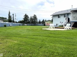 Expansive green lawn with a blue perimeter fence - 