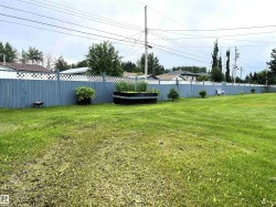 Expansive green lawn featuring a perimeter fence with a lattice top - 